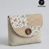 Beige linen button flap pouch with floral and polka dot patchwork design featuring a large wooden button closure. Completed sample of the Laurel PDF sewing pattern for a small clutch or cosmetic bag.