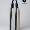 Handmade fabric wine carrier with blue straps and a grey geometric diamond pattern sitting next to a red wine bottle with a burgundy bow on a wooden table.