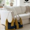 Two finished Aris hobo bags sitting on a white rug against a sofa. The bags feature a modern geometric color-block design in mustard yellow and navy blue with canvas straps. The image displays the Original and Large sizes of this digital sewing pattern.