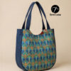 handmade curved tote bags in large and small sizes featuring a blue and teal geometric Art Deco print with navy blue trim and handles, displayed on a light wood floor next to a minimalist wooden chair.