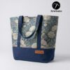 Finished Lyra canvas tote bag sewing pattern featuring a vintage blue floral tapestry upper, solid navy blue base, and navy webbing straps. The handmade bag is standing upright against a white background, showcasing this beginner DIY project.