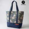 Finished Lyra canvas tote bag sewing pattern featuring a vintage blue floral tapestry upper, solid navy blue base, and navy webbing straps. The handmade bag is standing upright against a white background, showcasing this beginner DIY project.