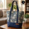 Finished Lyra canvas tote bag sewing pattern featuring a vintage blue floral tapestry upper, solid navy blue base, and navy webbing straps. The handmade bag is standing upright against a white background, showcasing this beginner DIY project.
